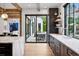 Bright kitchen highlighting marble countertops, dark cabinets, and sliding glass doors to a cozy outdoor dining space at 27 Polo Club Cir, Denver, CO 80209