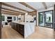 Spacious kitchen opens to living room and dining area featuring large marble island, wooden beams and hardwood flooring at 27 Polo Club Cir, Denver, CO 80209