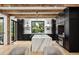 Modern kitchen featuring a marble waterfall island, black cabinetry, stainless steel appliances, and wood beam accents at 27 Polo Club Cir, Denver, CO 80209