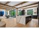 Open-concept kitchen featuring a large marble island, wood beams, and seamless flow to dining and outdoor spaces at 27 Polo Club Cir, Denver, CO 80209
