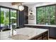 Close-up of kitchen showcasing marble island, stylish light fixture, dark cabinets, and backyard view at 27 Polo Club Cir, Denver, CO 80209