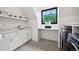 Bright laundry room with modern appliances, white cabinets, shelving, and a window with a view at 27 Polo Club Cir, Denver, CO 80209