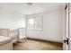 Bright bedroom with hardwood floors, a crib next to a window, and a door with black hardware at 2020 Teller St, Lakewood, CO 80214