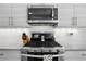 Close-up of a modern kitchen with stainless steel gas range, microwave, and sleek, minimalist cabinetry at 12497 W Virginia Ave, Lakewood, CO 80228