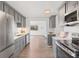 Well-lit kitchen with gray cabinetry, stainless steel appliances, and a view into an adjacent sun-lit living space at 306 N 14Th Ave, Brighton, CO 80601