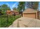 View of the detached garage and the charming brick home beyond the gated area at 2654 Forest St, Denver, CO 80207