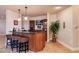 Basement bar with wood paneling, granite counters, display cabinetry, and pendant lighting at 8002 Galileo Way, Littleton, CO 80125