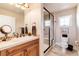 Bright bathroom featuring a glass-enclosed shower, granite countertops, and wood cabinetry at 8002 Galileo Way, Littleton, CO 80125