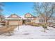 Beige two-story house with stone accents, a three-car garage, and a snow-covered yard at 23405 E Elmhurst Pl, Aurora, CO 80016