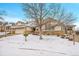 Two-story house with beige siding, stone accents, a three-car garage, and a snow-covered yard at 23405 E Elmhurst Pl, Aurora, CO 80016