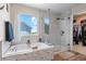 Bathroom with marble tiled shower and soaking tub next to a window and walk-in closet at 12491 E 106Th Pl, Commerce City, CO 80022