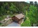 Aerial view of cabin home, nestled among tall trees and beautiful landscaping, including a pond and outdoor patio at 1345 Witter Gulch Rd, Evergreen, CO 80439