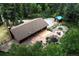 Aerial view of cabin home, featuring stone patio, water feature, outbuilding and backing onto trees at 1345 Witter Gulch Rd, Evergreen, CO 80439