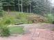 Spacious backyard with lush landscaping, tiered garden beds, and a stone patio, ideal for gardening and relaxation at 1345 Witter Gulch Rd, Evergreen, CO 80439