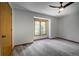 Empty bedroom with plush carpeting and a large window overlooking a wooded backyard at 1345 Witter Gulch Rd, Evergreen, CO 80439