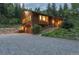 Side exterior of a wood home featuring garage, stone accents, and a gravel driveway at 1345 Witter Gulch Rd, Evergreen, CO 80439