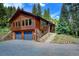 Beautiful two-story house featuring a stone foundation, wood siding, and a two-car garage, with manicured landscaping at 1345 Witter Gulch Rd, Evergreen, CO 80439