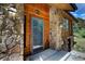 Close up of front door with address number above, with wood and stone exterior at 1345 Witter Gulch Rd, Evergreen, CO 80439