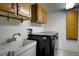 Functional laundry room equipped with a modern washer, sink, and storage cabinets for convenience and organization at 1345 Witter Gulch Rd, Evergreen, CO 80439
