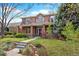 Charming two-story brick home featuring a well-manicured lawn, mature trees, and inviting curb appeal at 1215 S Ogden St, Denver, CO 80210