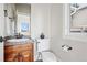 Cozy powder room with stone countertop, undermount sink, toilet, and window to the exterior at 1215 S Ogden St, Denver, CO 80210