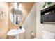 This powder room has a pedestal sink, round mirror, and cabinet above the toilet at 9735 E 112Th Pl, Commerce City, CO 80640