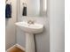 Bathroom featuring white pedestal sink, neutral walls, and wood trim at 767 Roslyn St # 20, Denver, CO 80230
