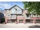 Townhome featuring brick facade, private balconies, and attached garages at 767 Roslyn St # 20, Denver, CO 80230