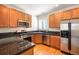Updated kitchen featuring wood cabinets, granite counters, and stainless steel appliances at 767 Roslyn St # 20, Denver, CO 80230