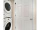 Laundry room features a stacked washer and dryer next to a white door at 767 Roslyn St # 20, Denver, CO 80230