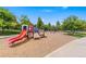 Community playground features a red slide and climbing structures surrounded by mature trees at 767 Roslyn St # 20, Denver, CO 80230