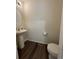A half bathroom features a pedestal sink, toilet, and dark wood-look flooring at 47314 Iris Ave, Bennett, CO 80102