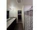 Bright bathroom featuring a granite vanity, walk-in closet, and a shower with decorative curtain at 47314 Iris Ave, Bennett, CO 80102
