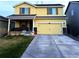 Two-story yellow home with a covered front porch, a two car garage, and a well-manicured lawn at 47314 Iris Ave, Bennett, CO 80102