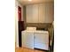 Practical laundry room with a washer, dryer, storage cabinets, and wooden floor at 1778 S Lee St, Lakewood, CO 80232