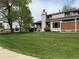 Exterior of home with lush green lawn, mature trees, and well kept yard at 1778 S Lee St, Lakewood, CO 80232