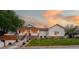 Charming home featuring a welcoming front porch, stone accents, and a lush green lawn at sunset at 5372 W 68Th Ave, Arvada, CO 80003