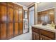 Functional bathroom with wood cabinets, wallpaper details, and standard fixtures at 8836 E Phillips Pl, Centennial, CO 80112