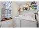 Functional laundry room with a washer, dryer, built-in shelving, and a window for natural light at 8836 E Phillips Pl, Centennial, CO 80112