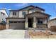 Two-story home with brown accents, a two-car garage, stone pillar accents, and a covered porch at 9082 Telluride Ct, Commerce City, CO 80022