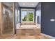Elegant bathroom showcasing a soaking tub, glass shower, and serene blue walls with natural lighting at 3858 W 117Th Ct, Westminster, CO 80031