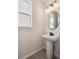 Modern powder room featuring a pedestal sink, round mirror, and light fixtures at 1269 Penner Dr, Erie, CO 80026