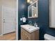 Stylish bathroom with blue walls, a wood vanity, a mirror, and a white door at 4467 Trailside Ln, Castle Rock, CO 80109