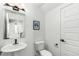 Bright half bathroom featuring a pedestal sink, toilet, and decorative wall art at 6396 Nelson Ct, Arvada, CO 80004