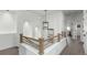 Bright hallway featuring wood railing, modern light fixture, and hardwood floors at 6396 Nelson Ct, Arvada, CO 80004