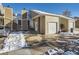 Tan siding townhouse with white door, attached garage, and snow-covered walkway at 11860 Harrison St, Thornton, CO 80233