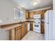 Galley style kitchen with light wood cabinets and white appliances at 11860 Harrison St, Thornton, CO 80233