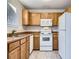 Kitchen with wood cabinets, white appliances, and double sink at 11860 Harrison St, Thornton, CO 80233