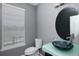 Modern powder room featuring blue glass sink, round mirror, and gray walls at 338 Mt Wilson St, Brighton, CO 80601