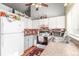 Well-lit kitchen featuring white cabinets, appliances, and practical brick backsplash at 17665 E Temple Dr, Aurora, CO 80015